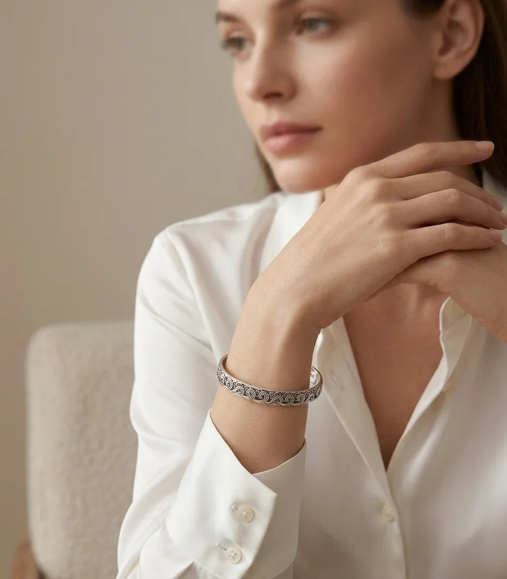 femme en chemise blanche léger zoom sur le bracelet jonc Velya de couleur argenté, avec de motif gravé en vague