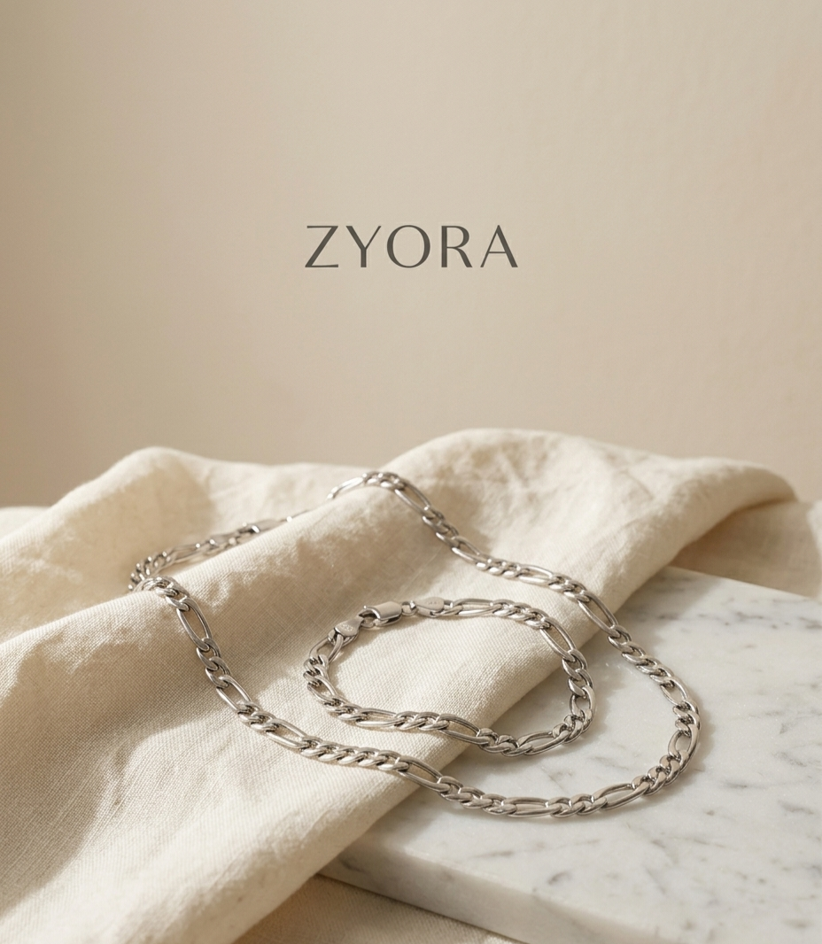 Collier et bracelet de couleur argentés Nexo délicatement posés sur un tissu clair, parure de bijoux en acier inoxydable 316L waterproof Zyora