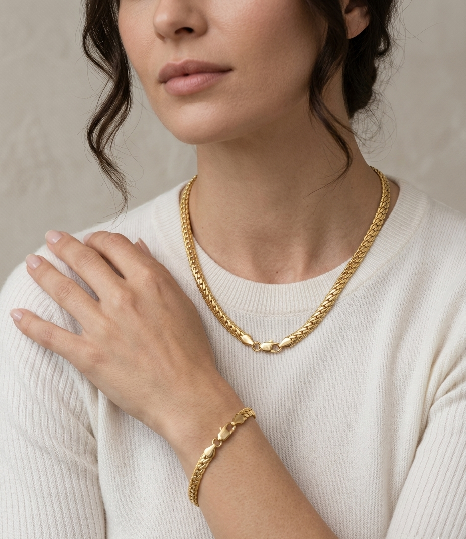 Femme élégante portant l'ensemble de bijoux Velis avec collier et bracelet maille serpent plate couleur doré en acier inoxydable 316LZyora