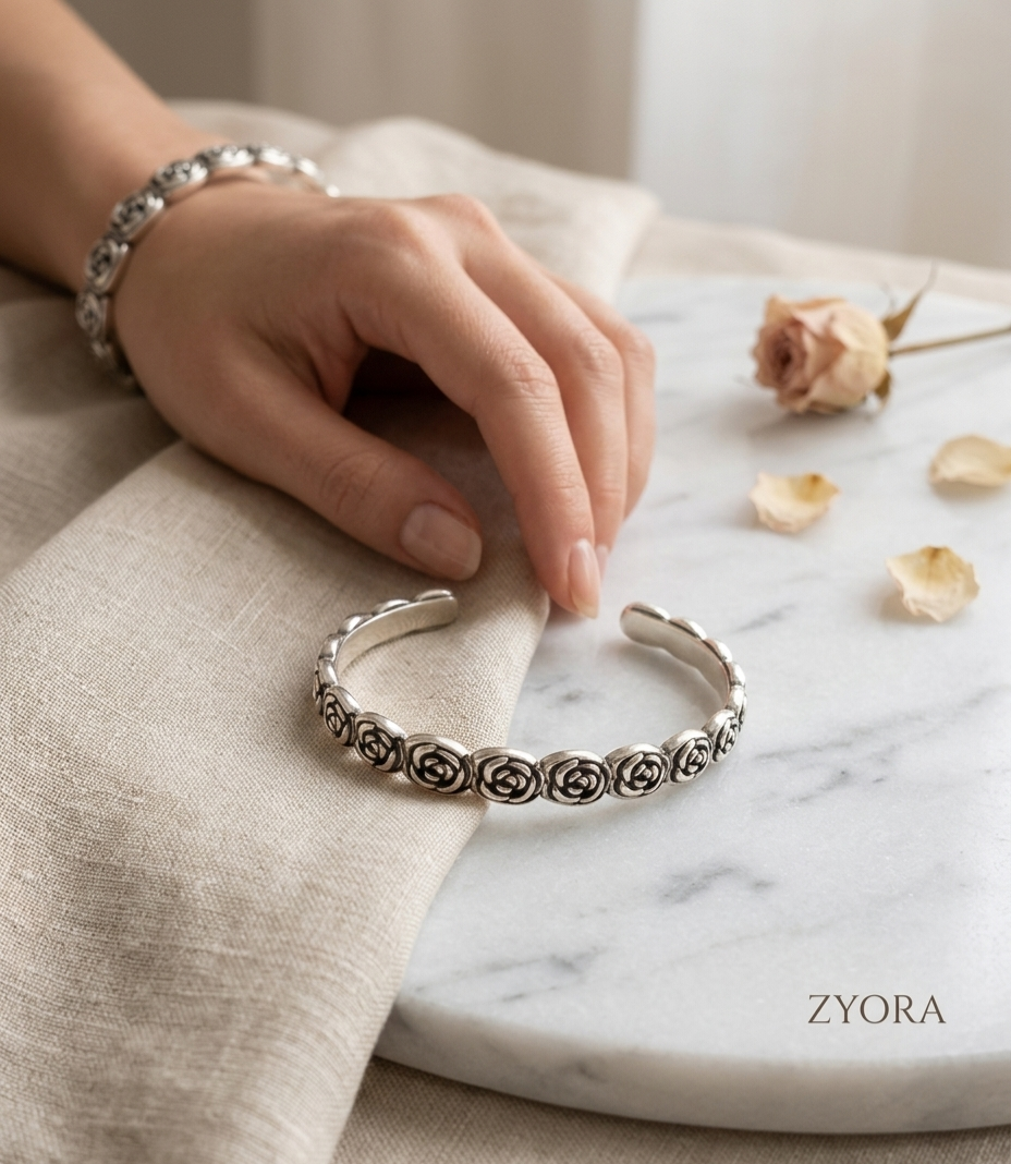 Main de femme posée sur un tissu portant le bracelet jonc fleuri Roséa waterproof, en acier inoxydable 316L Zyora